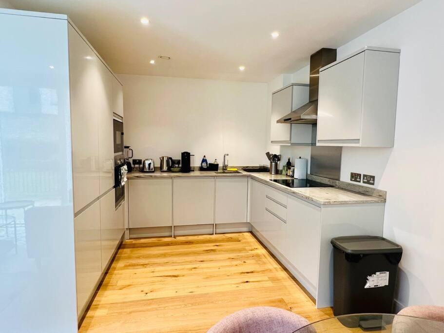 a kitchen with white cabinets and a wooden floor at Luxury 2 Bed 2 Bathroom apt near tube station! in London