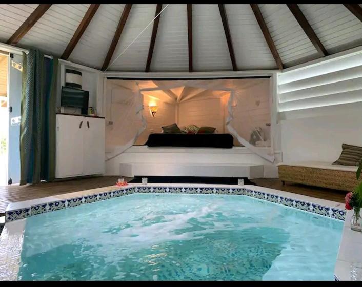 a large swimming pool in a room with a bed at Le grand palm gîte tobago in Les Basses