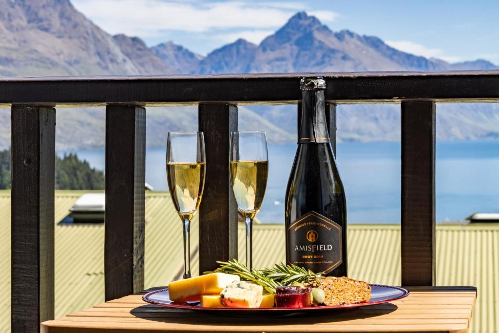 a table with two glasses of wine and a plate of food at Magic mountain Vista in Queenstown
