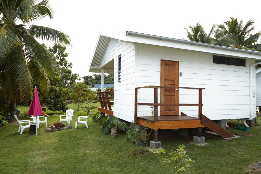 a small white house with chairs and a porch at Le dauphin de te ava iti in Matiti