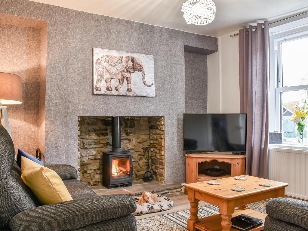 una sala de estar con chimenea y una foto de elefante en la pared en Cwmcarn Cottage, en Crosskeys