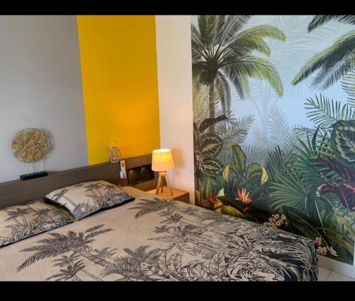 una camera da letto con un letto e un murale tropicale sul muro di Studio Cap Caraibes, piscine, accès plage, nouvelle Wifi haut debit a Saint-François