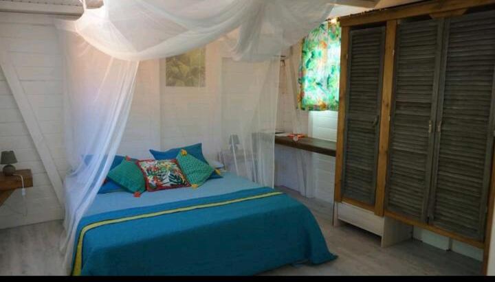 Le grand palm gîte filao في ليه باسي: غرفة نوم بسرير ازرق ونافذة