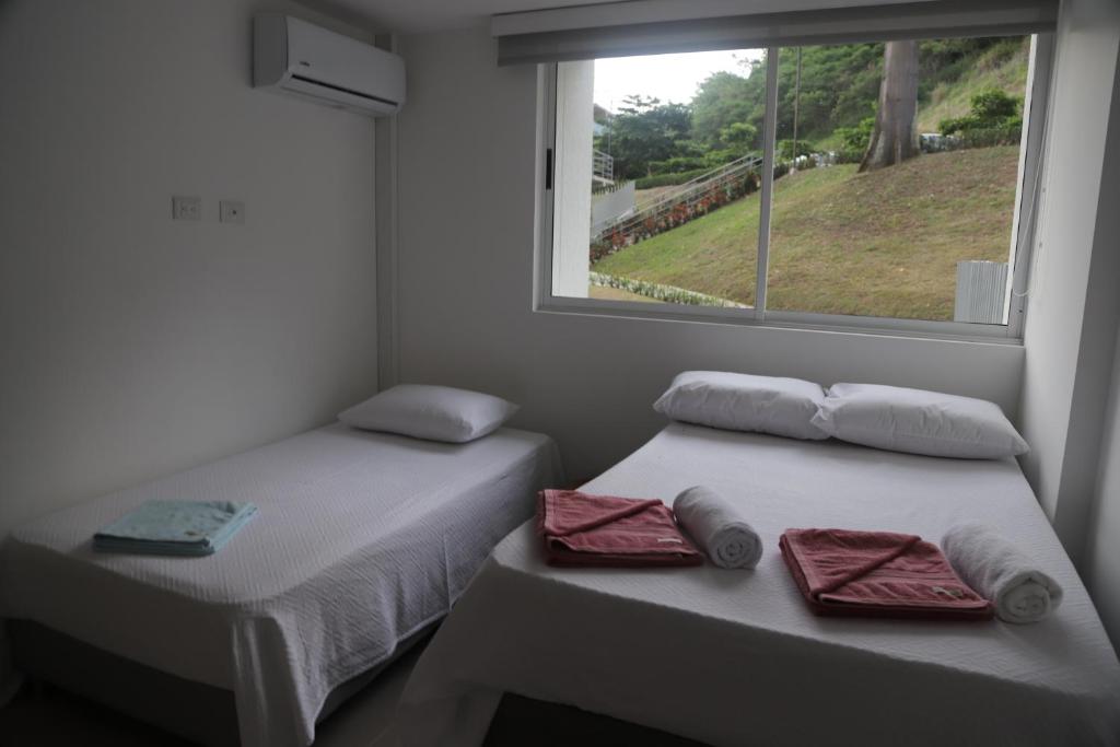 2 aparte bedden in een kamer met een raam bij Estadía, hermosos apartasoles en Santafé de Antioquia in Santa Fe de Antioquia