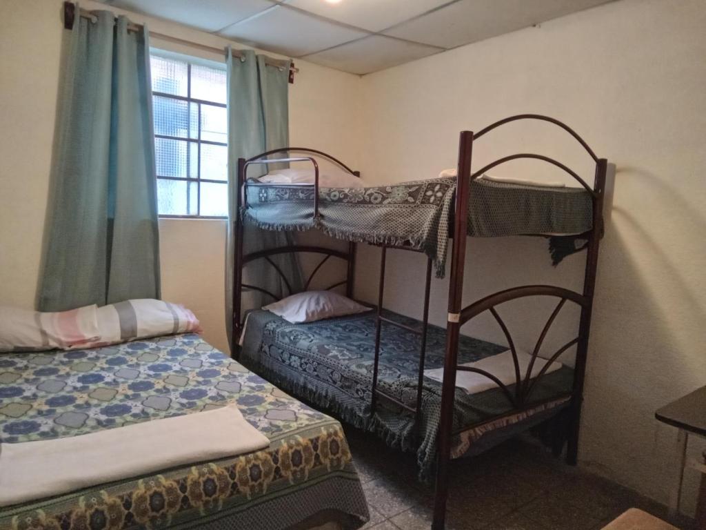 1 dormitorio con 2 literas y ventana en Huellas Hostal Antigua, en Antigua Guatemala