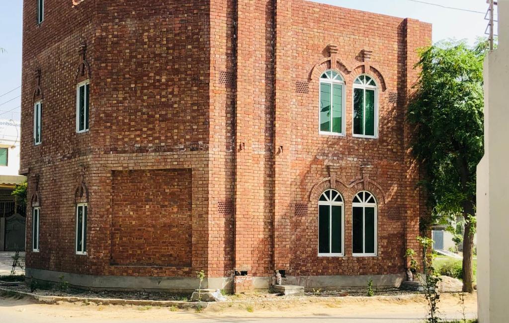 a red brick building with windows on the side of it at Hosteller - Hostel & Hotel Johar Town Lahore in Lahore