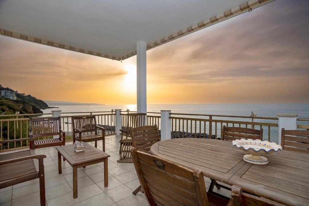 un tavolo in legno con sedie su un balcone con vista sull'oceano di Appartamento fronte mare con parcheggio gratuito a Pizzo