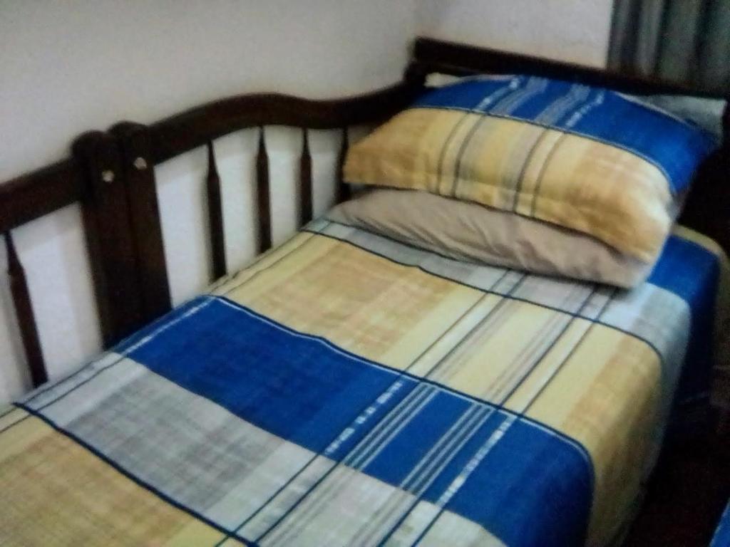 uma cama com um cobertor e uma almofada em Cantinho do Thiê em Paqueta