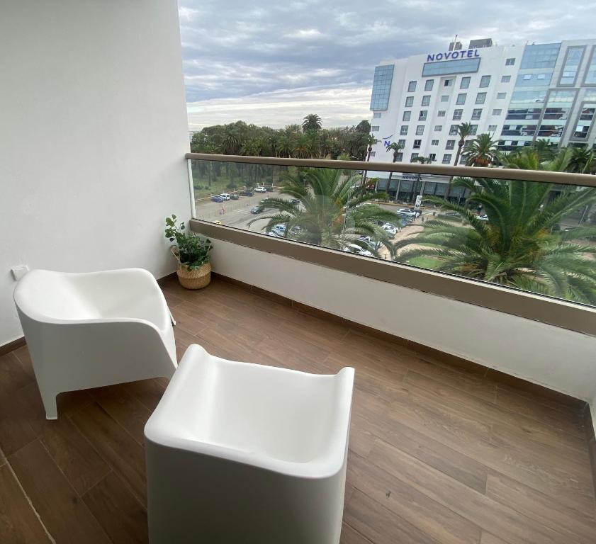 a balcony with a white chair and a view of a building at Luxueux appartement avec vue panoramique in Mohammedia