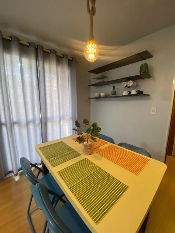 a dining room table with chairs and a light fixture at Residencial Cayenne in Caxias do Sul
