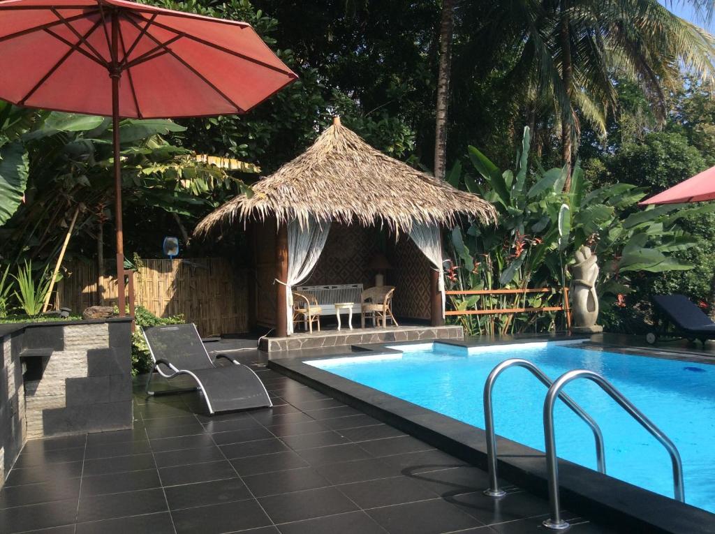 a swimming pool with a red umbrella and a table at Oase Van Java in Salatiga