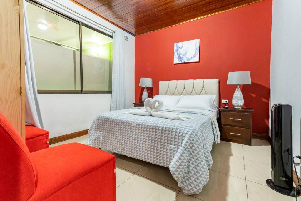 ein Schlafzimmer mit einem Bett und einer roten Wand in der Unterkunft Private bedroom 10 minutes from the SJO airport in Alajuela