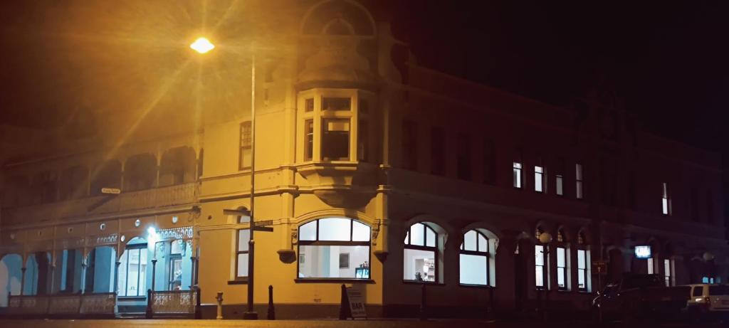 een geel gebouw 's nachts met een straatlicht bij Leura Hotel in Camperdown