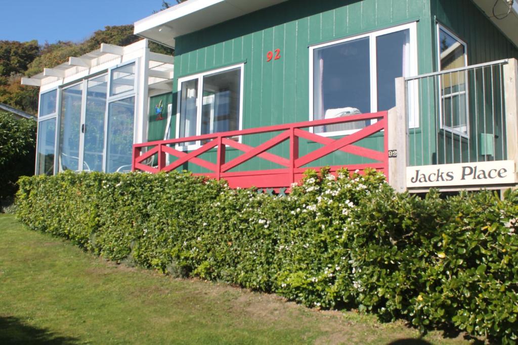 a green and red house with a sign in front of it at Jacks place in Moeraki