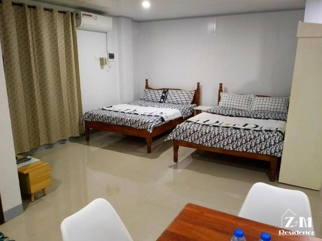a room with two beds and a table and chairs at ZM Residence in Dapa