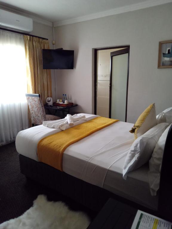 a hotel room with a large bed and a window at Antique Home BnB in Gaborone