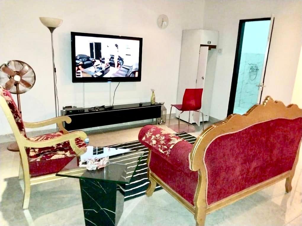 a living room with two chairs and a flat screen tv at Yazmin’s studio apartments in Lamin