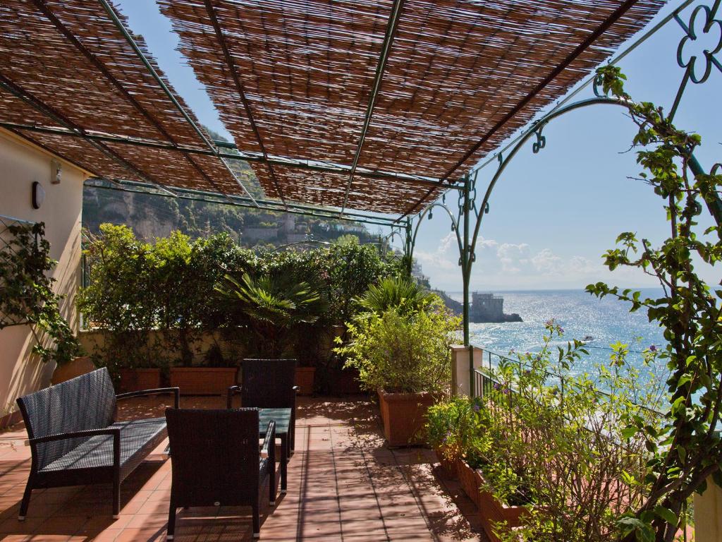 un patio con mesa, sillas y el océano en Hotel Sole en Maiori