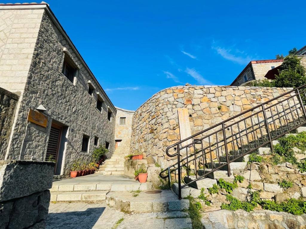 a stone building with stairs next to a stone wall at 芹壁山城民宿 Chinbe Hill Village House B&B in Beigan