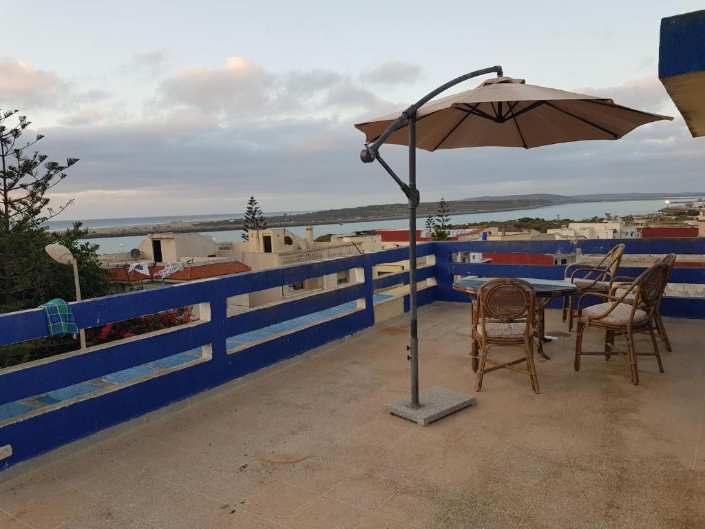 a table and chairs with an umbrella on a balcony at Etage Villa Mehdia Amrya Plage N 277 in Kenitra