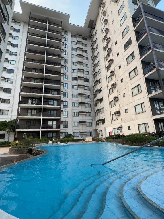 a large swimming pool in front of two apartment buildings at JmR Serin West studio unit pay by Gcash or cash only in Tagaytay