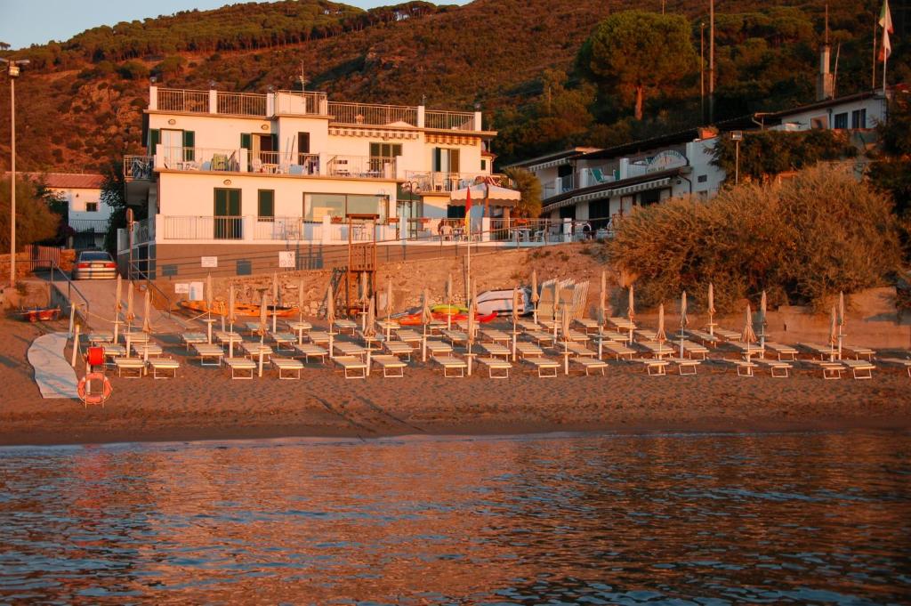 a group of chairs on a beach next to the water at Appartamenti Villa Miramare in Capoliveri