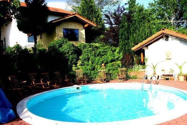 una gran piscina con sillas y una casa en Landhaus Glashütt, en Sankt Englmar