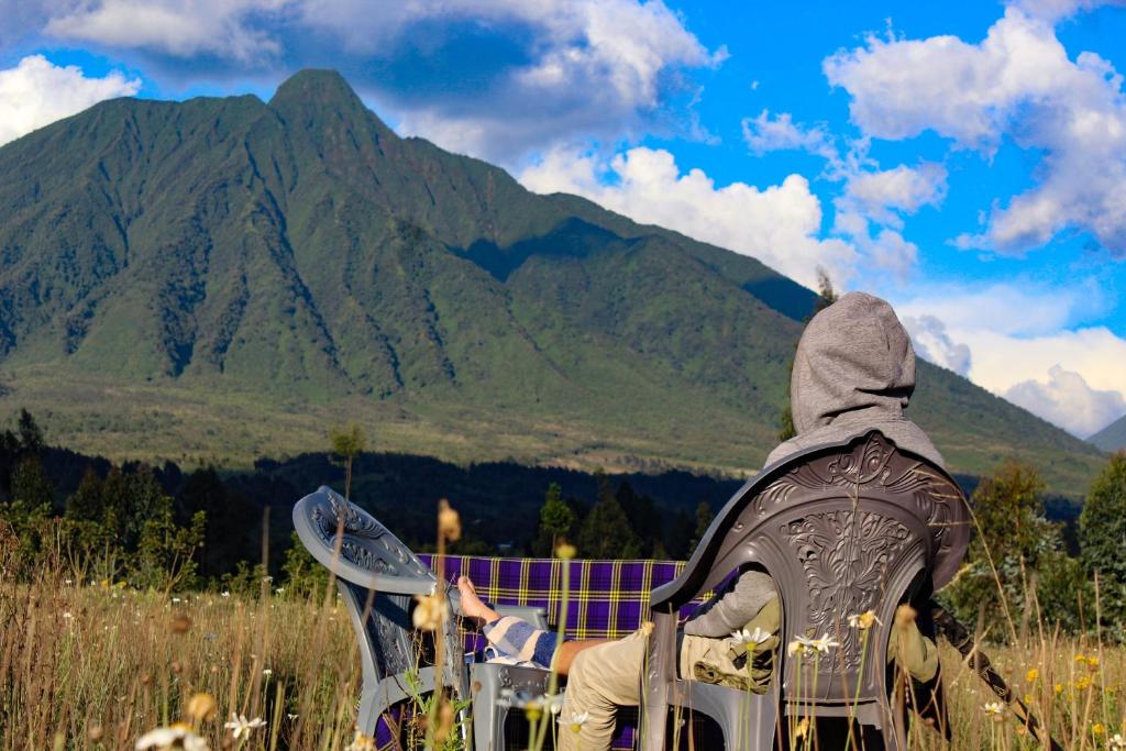 Nyarugina的住宿－Under Volcanoes View Guest House，坐在椅子上看山的人