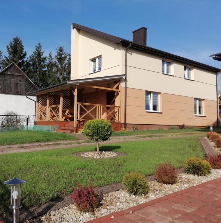 a large white house with a tree in the yard at Apartament z tarasem in Bodzentyn