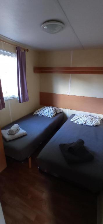 two beds in a small room with a window at CAMPING LE BEL AIR Mobil home L&#39;OLIVIER 4 personnes in Limogne-en-Quercy