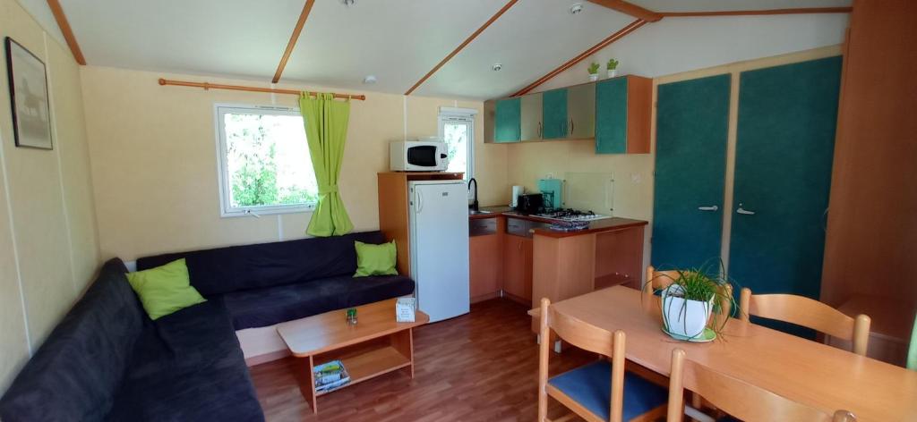 a living room with a couch and a table and a kitchen at CAMPING LE BEL AIR Mobil home L'OLIVIER 4 personnes in Limogne-en-Quercy