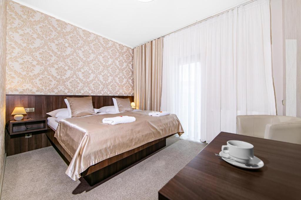 プルゼニにあるホテル ラウドナのベッドとテーブルが備わるホテルルームです。