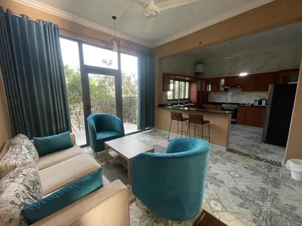 ein Wohnzimmer mit einem Sofa und Stühlen sowie eine Küche in der Unterkunft Rose Guesthouse in Al ‘Aqar