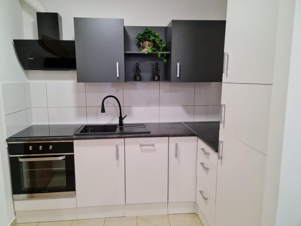 a white kitchen with white cabinets and a sink at Apartman Vinyl - self chek-in in Osijek