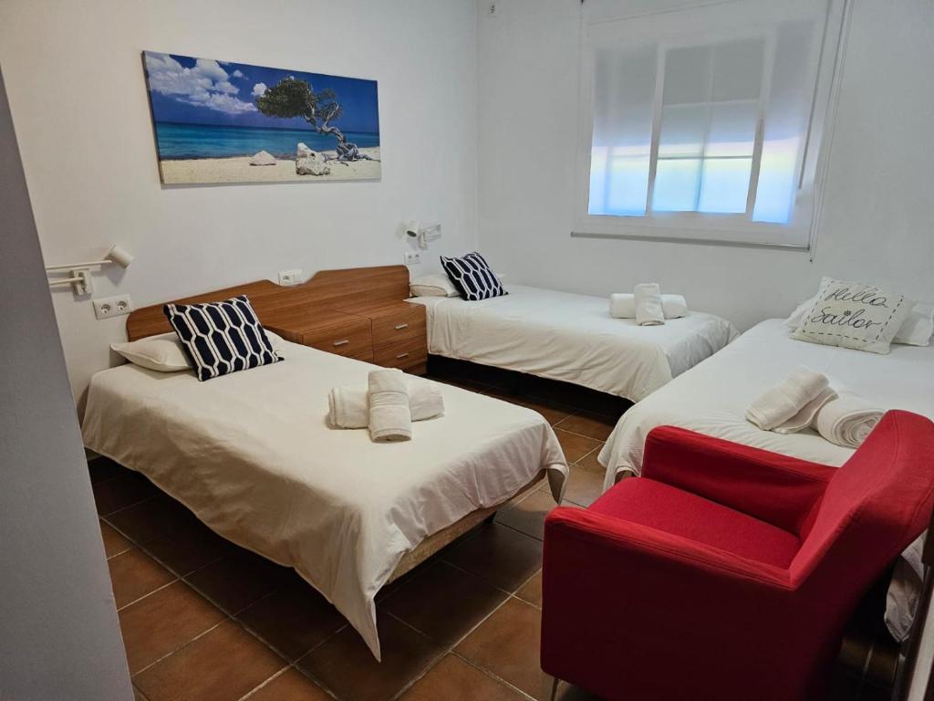 Zimmer mit 3 Betten und einem roten Stuhl in der Unterkunft Villa Torrealta, 4000 m2, estancia mínima en verano 7 días de sábado a sábado in Cádiz