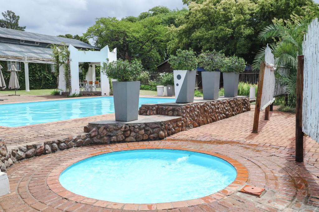 a large swimming pool with a brick walkway around it at Lodge Laske Nakke in Lydenburg