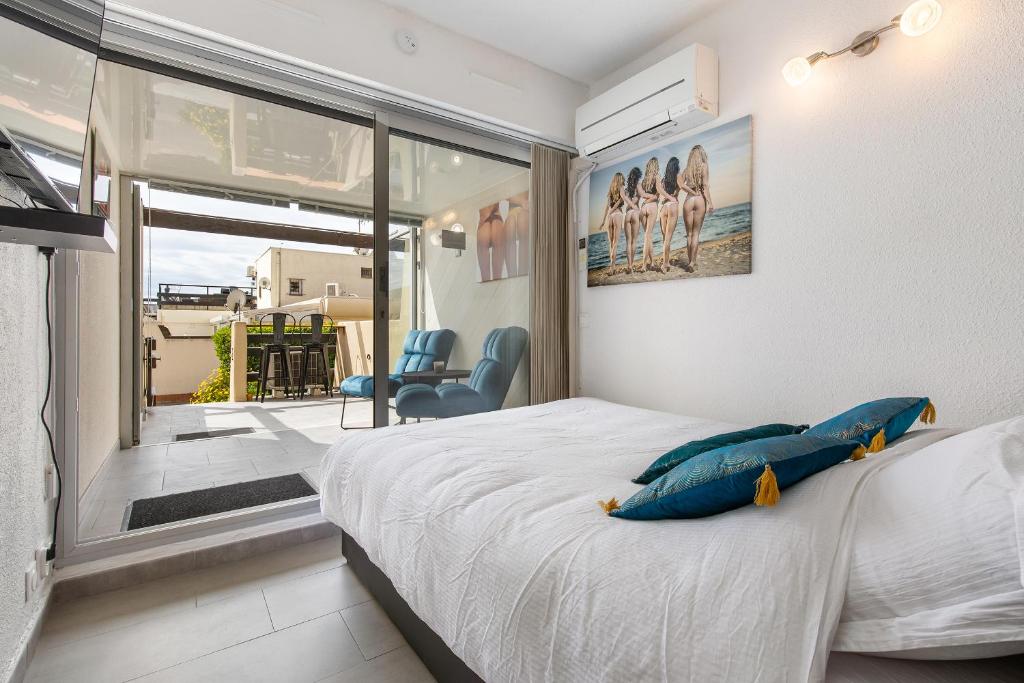 une chambre avec un lit avec des oreillers bleus et une fenêtre dans l'établissement CAP AGDE NATURISTE STUDIO PORT NATURE 3, au Cap d'Agde