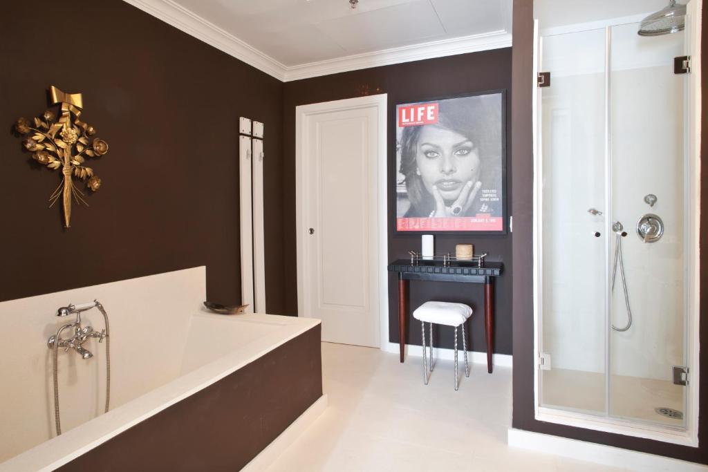 a bathroom with a tub and a poster of a woman at Capri Tiberio Palace - The Leading Hotels of the World in Capri