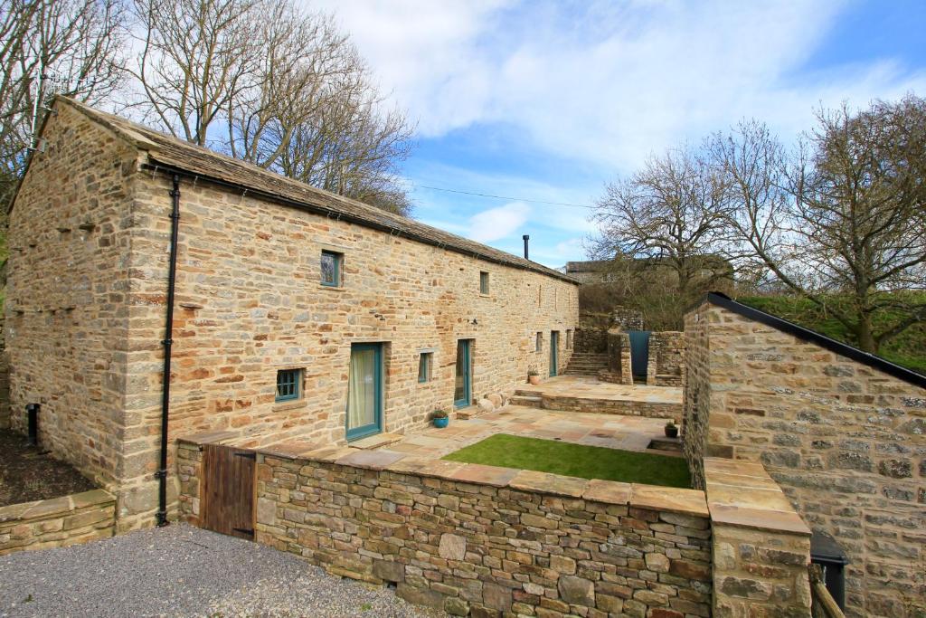 an old brick building with a courtyard in front of it at Fremington Hall Farm, Reeth, Swaledale in Reeth