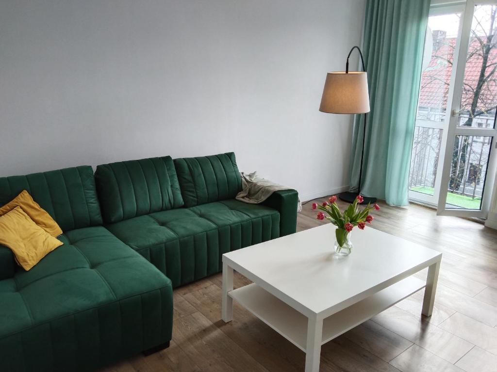 a living room with a green couch and a table at Tabago Studio 7 in Kędzierzyn-Koźle