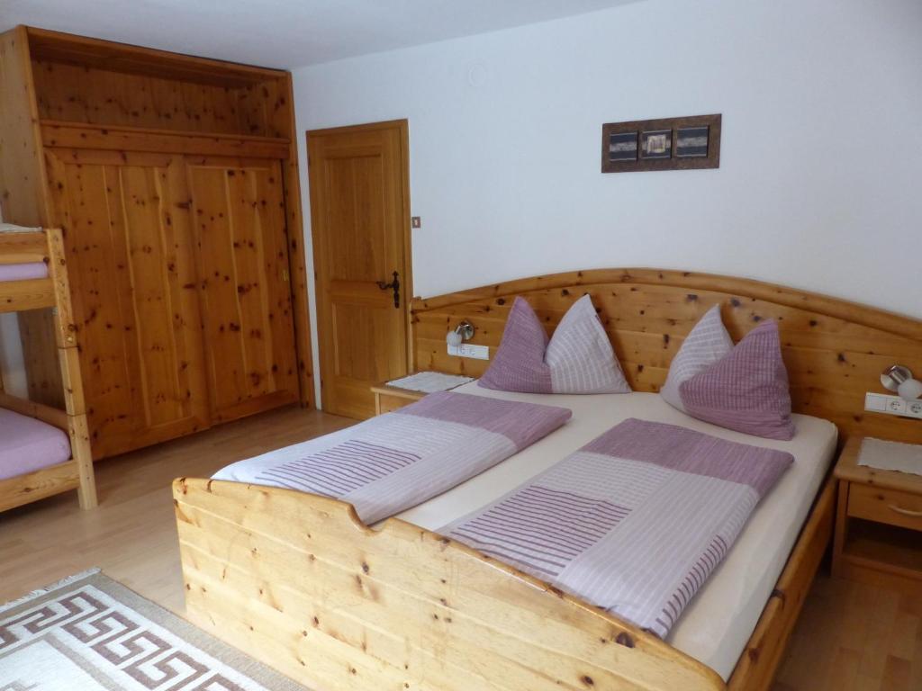 1 dormitorio con cama de madera y almohadas moradas en Apartment Telser en Lasa