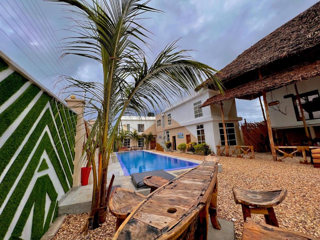 a pool with a wooden table and chairs next to a house at VICK Boutique Hotel with NEW power backup in Nungwi