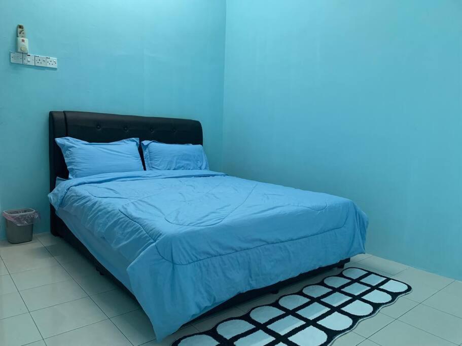a bed in a room with a blue wall at Homestay 69 in Hutan Melintang