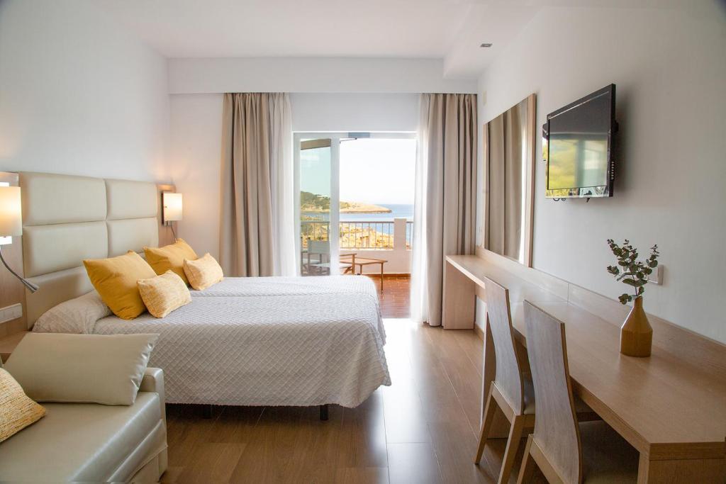 Habitación de hotel con cama y sofá en Hostal La Cigüeña en Portinatx