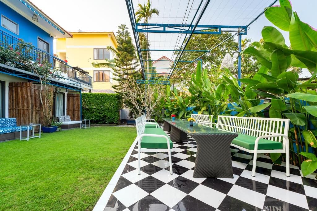 eine Terrasse mit einem karierten Boden sowie einem Tisch und Stühlen in der Unterkunft Lavini Hoian Boutique Villa in Hoi An