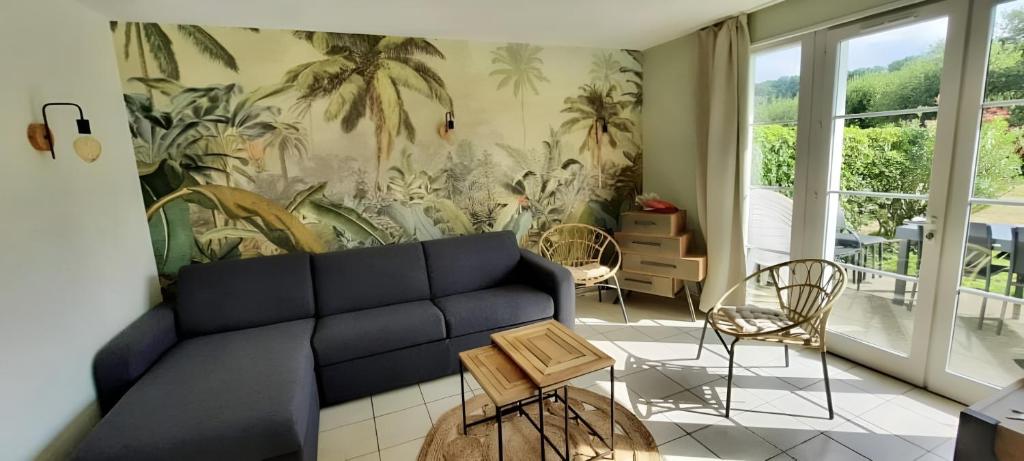 ein Wohnzimmer mit einem blauen Sofa und einem Palmenmilch in der Unterkunft Maison de vacances 4/6p au Golf de Port Bourgenay in Talmont
