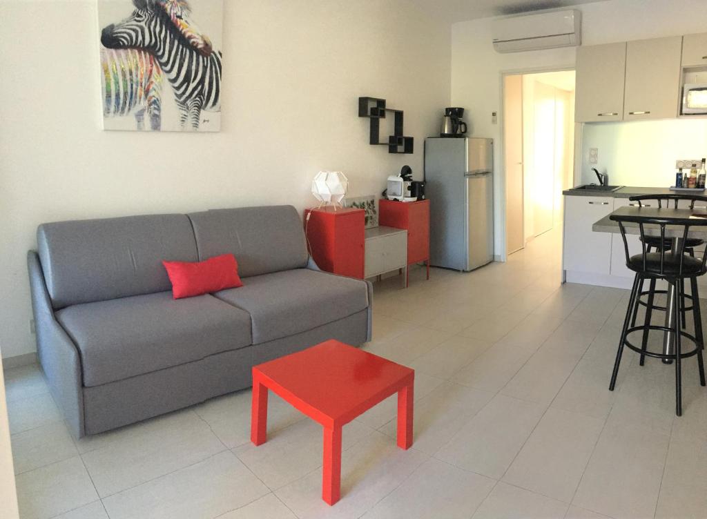 - un salon avec un canapé et un tabouret rouge dans l'établissement La Pinède Calvi, à Calvi