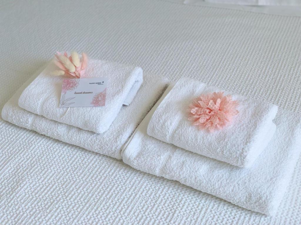 two towels with a flower on them on a bed at Fairy home Porto Heli in Porto Heli