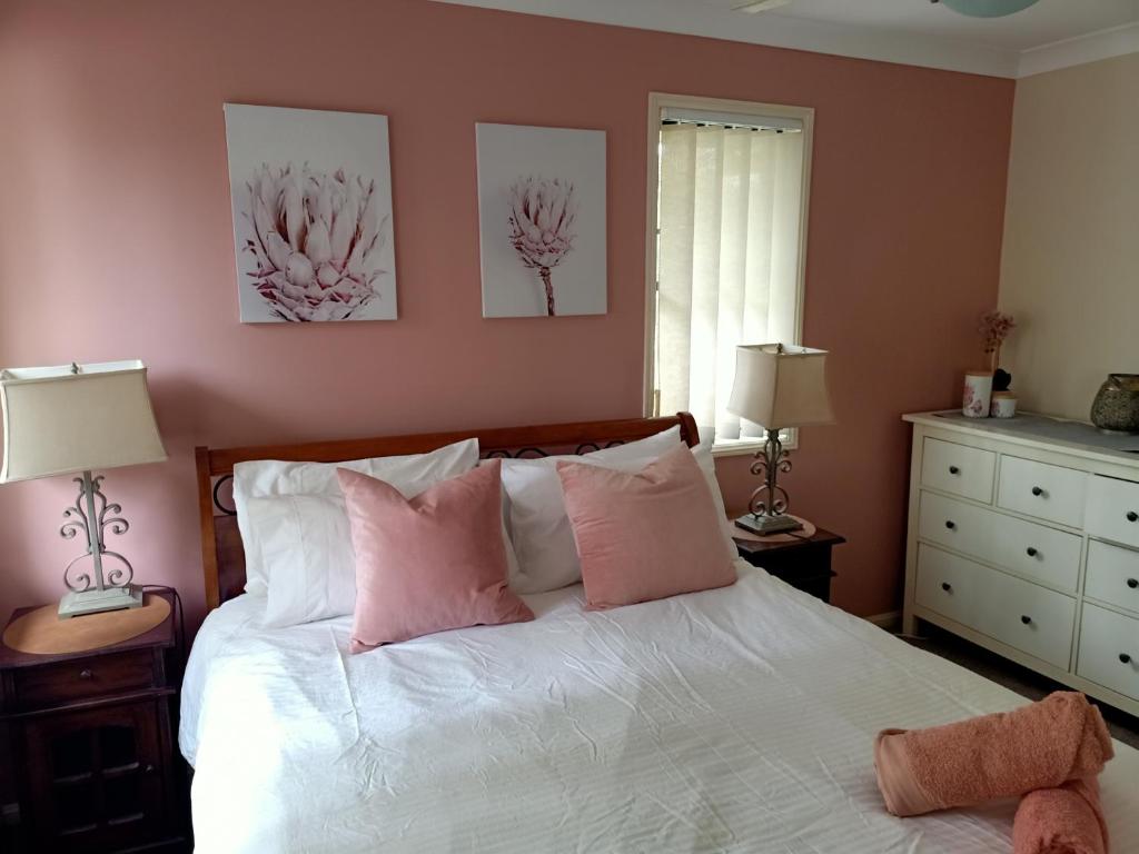 a bedroom with a white bed with pink pillows at Tingalpa Townhouse Treat in Brisbane