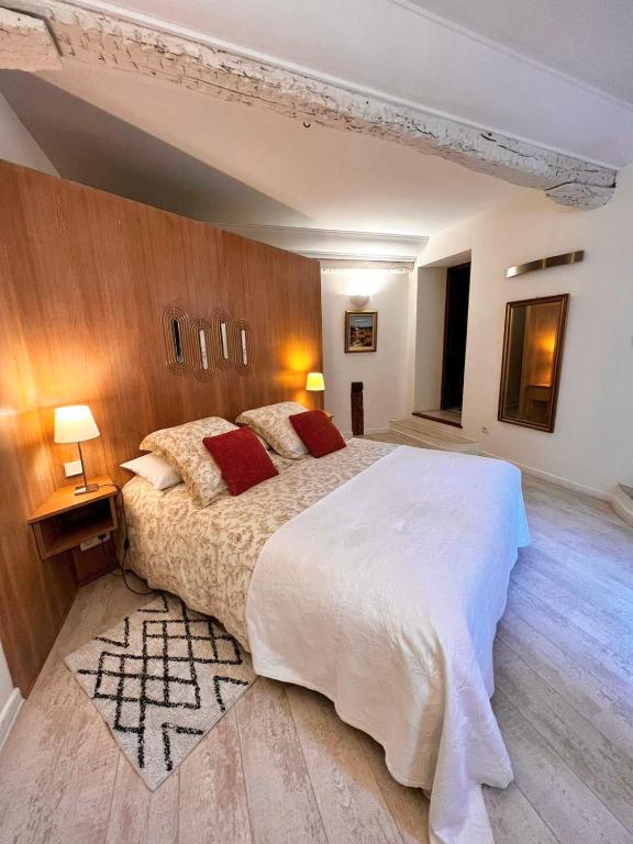 - une chambre avec un grand lit et un mur en bois dans l'établissement L'élégante - maison de ville avec bains à remous - parking inclus, à Saint-Paul-de-Vence